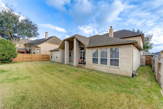 rear view of property featuring a lawn, a fenced backyard, a chimney, a patio area, and brick siding