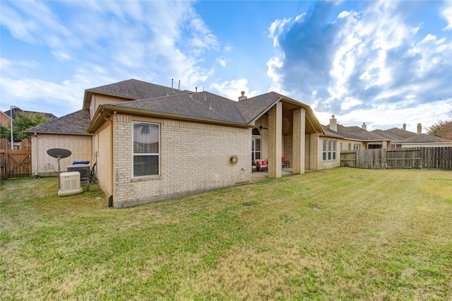 rear view of property featuring brick siding, a yard, and fence