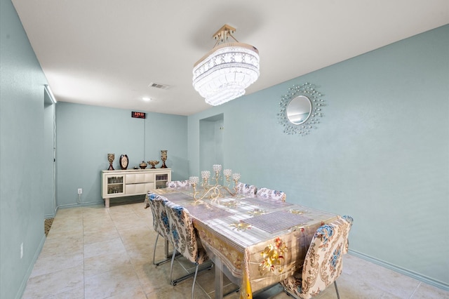 tiled dining room with a notable chandelier