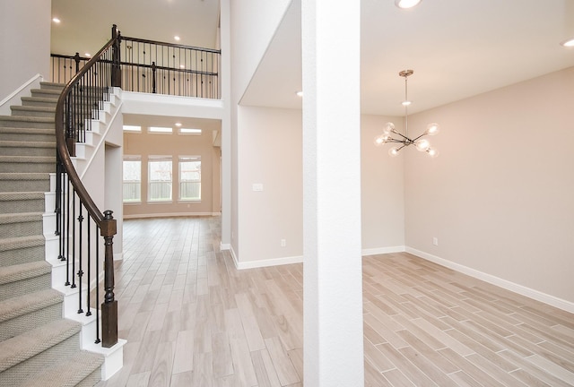 foyer entrance featuring an inviting chandelier, light hardwood / wood-style floors, and a high ceiling