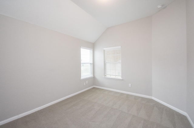 carpeted spare room with lofted ceiling