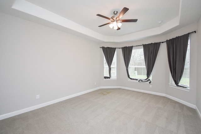 carpeted empty room featuring ceiling fan and a tray ceiling