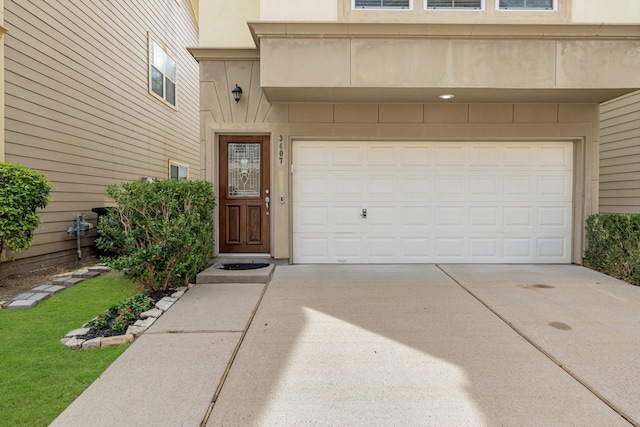 doorway to property with concrete driveway and an attached garage