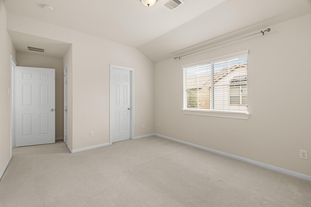 unfurnished bedroom with lofted ceiling, visible vents, light carpet, and baseboards