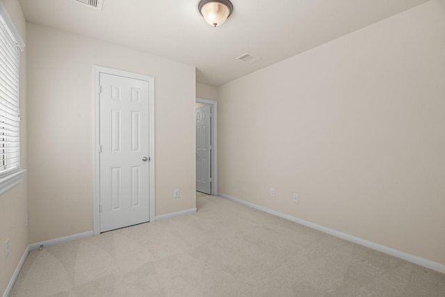 unfurnished bedroom with baseboards, visible vents, and light colored carpet