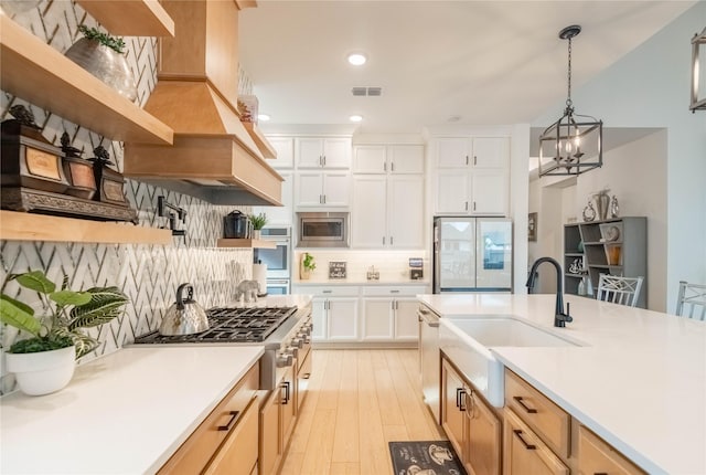 kitchen featuring hanging light fixtures, stainless steel appliances, sink, white cabinets, and decorative backsplash