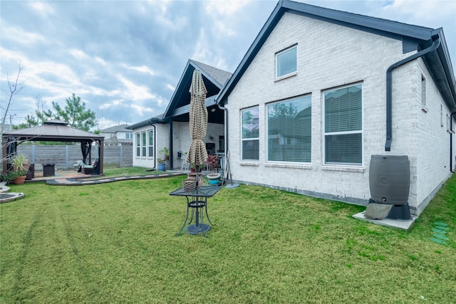 back of property with a yard and a gazebo