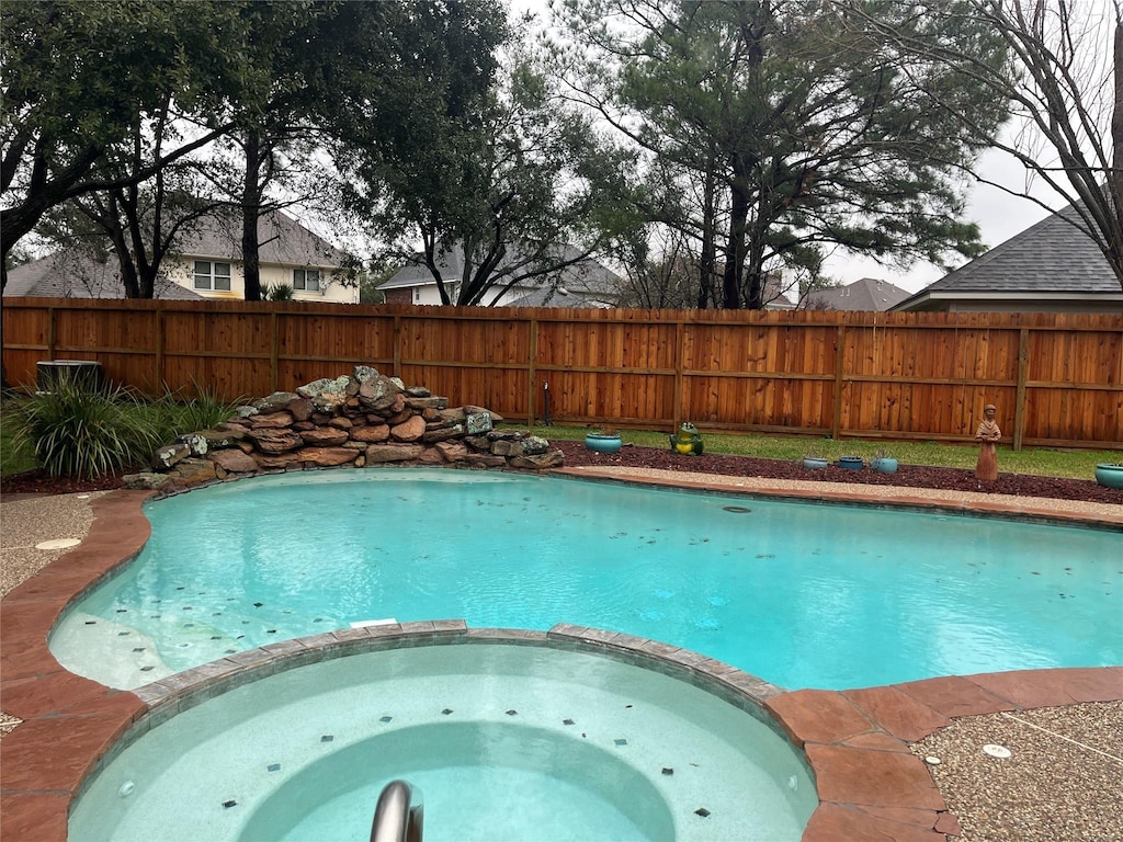 view of swimming pool with a pool with connected hot tub and fence