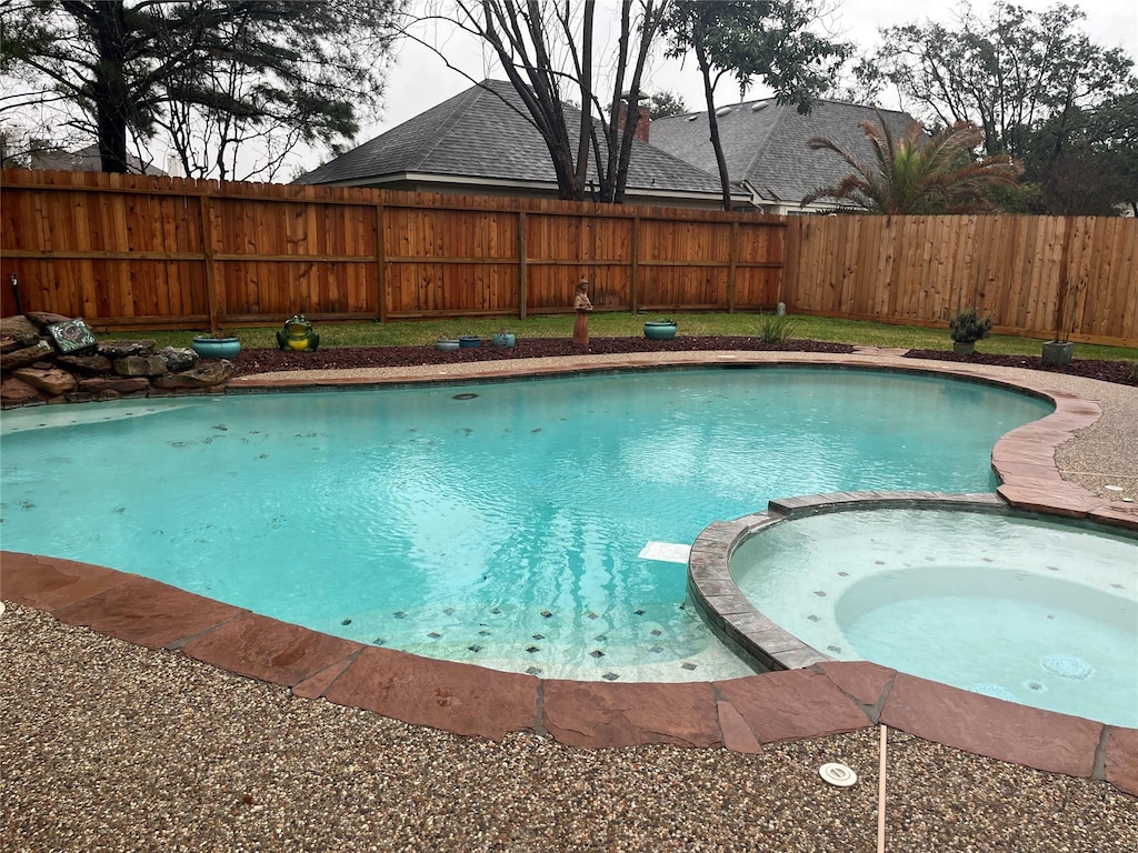 view of pool with a pool with connected hot tub and fence