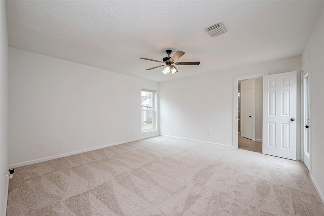 empty room with ceiling fan, light colored carpet, and a textured ceiling