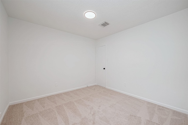 spare room with light carpet and a textured ceiling