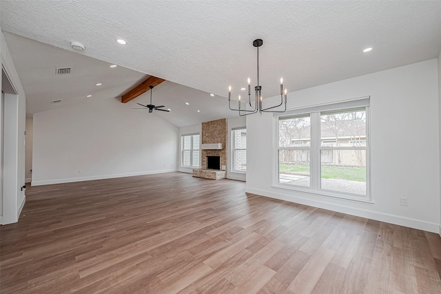 unfurnished living room featuring lofted ceiling with beams, a brick fireplace, hardwood / wood-style floors, and a textured ceiling