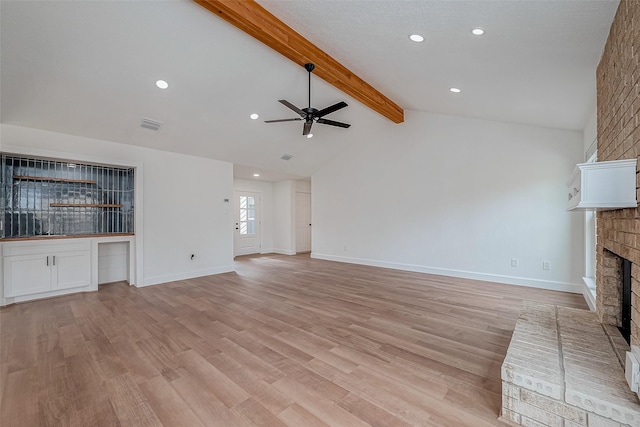 unfurnished living room with lofted ceiling with beams, sink, ceiling fan, light hardwood / wood-style floors, and a brick fireplace