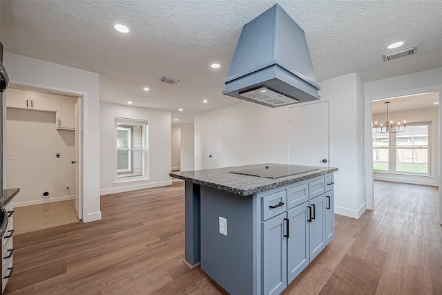 kitchen featuring light hardwood / wood-style flooring, a center island, island exhaust hood, black electric cooktop, and a chandelier