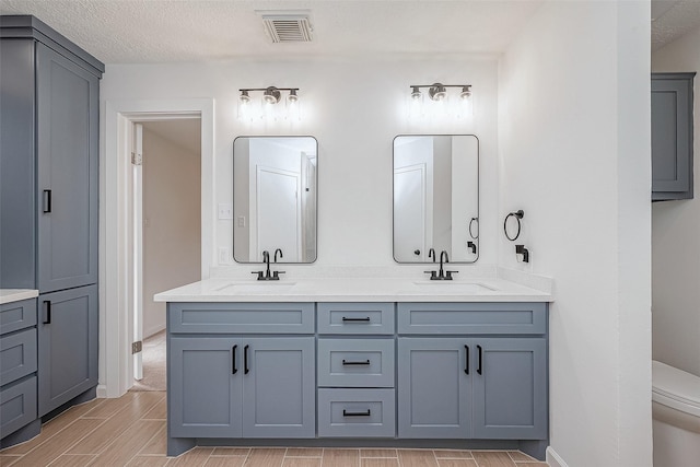 bathroom with vanity, a textured ceiling, and toilet