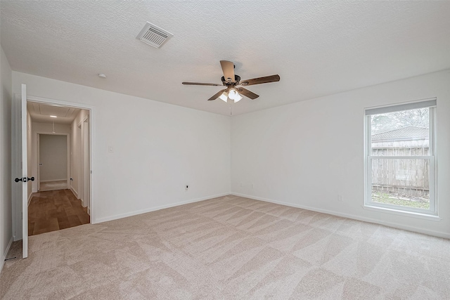 unfurnished room with ceiling fan, light carpet, and a textured ceiling