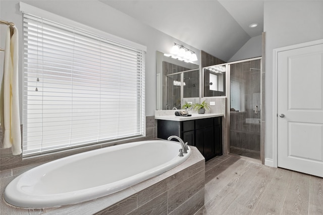 full bath with lofted ceiling, a garden tub, wood finished floors, vanity, and a shower stall