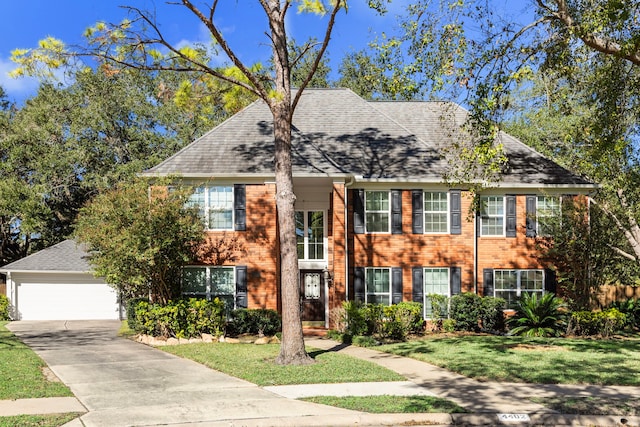 colonial-style house featuring driveway, a garage, brick siding, a shingled roof, and a front yard