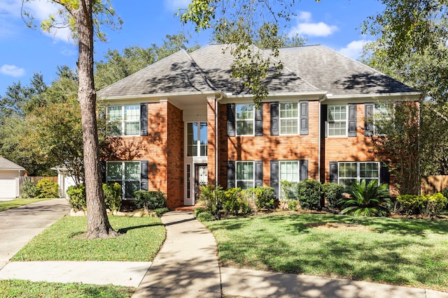 view of front of home with a shingled roof, a front lawn, and brick siding