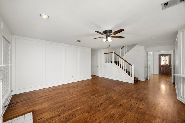 unfurnished living room with a ceiling fan, wood finished floors, stairs, and visible vents