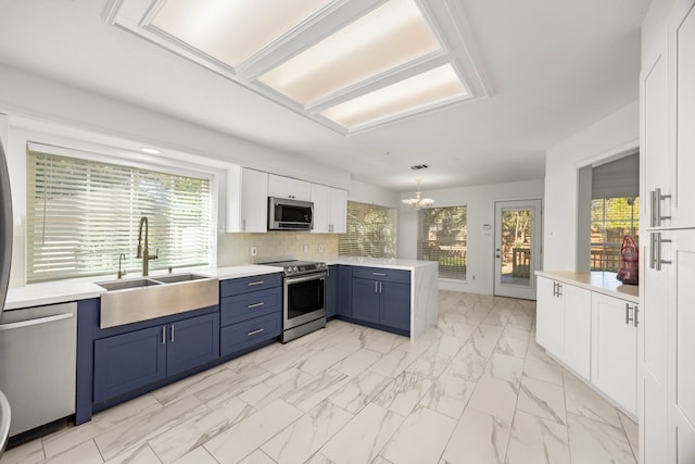 kitchen with blue cabinets, sink, white cabinets, hanging light fixtures, and stainless steel appliances