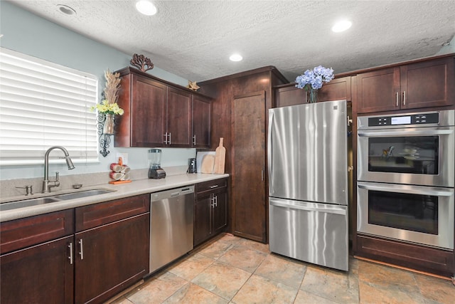 kitchen featuring sink, dark brown cabinets, a textured ceiling, and appliances with stainless steel finishes