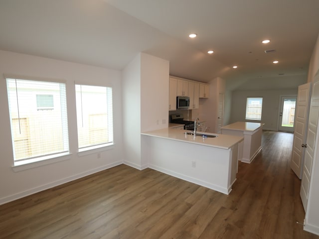 26235 Astral Way, La Marque, TX 77568 - kitchen with stainless steel appliances, a peninsula, dark wood-style flooring, white cabinetry, and lofted ceiling