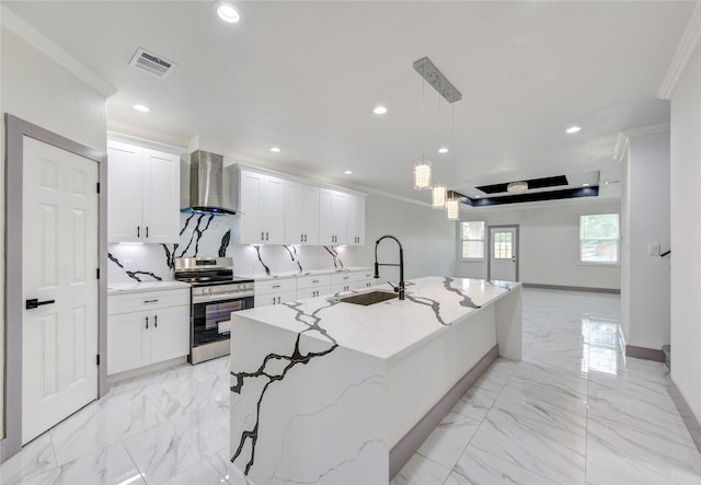 kitchen with stainless steel electric range oven, pendant lighting, sink, wall chimney range hood, and a center island with sink