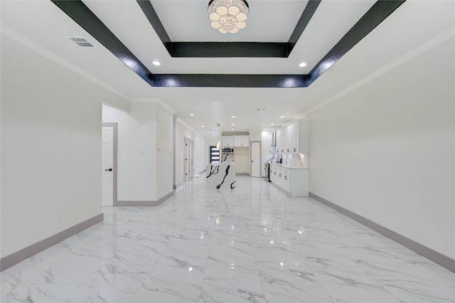 hall featuring crown molding, a tray ceiling, and a high ceiling