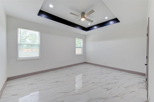 empty room featuring ceiling fan and a raised ceiling