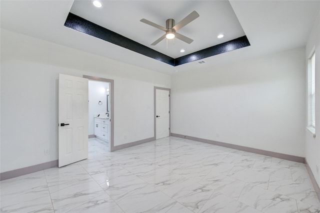 empty room featuring a raised ceiling and ceiling fan