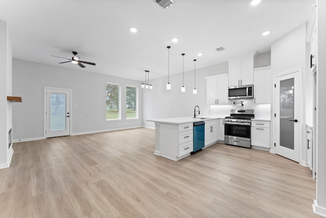 kitchen with visible vents, open floor plan, a peninsula, stainless steel appliances, and a sink