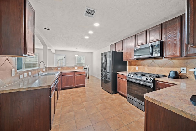 kitchen with sink, appliances with stainless steel finishes, backsplash, decorative light fixtures, and kitchen peninsula