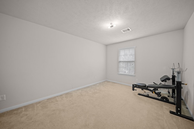 workout room with light carpet and a textured ceiling