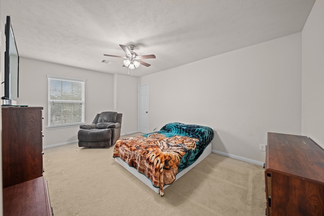 carpeted bedroom featuring ceiling fan and a textured ceiling