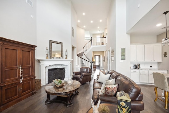 living room featuring a premium fireplace, dark hardwood / wood-style floors, and a high ceiling