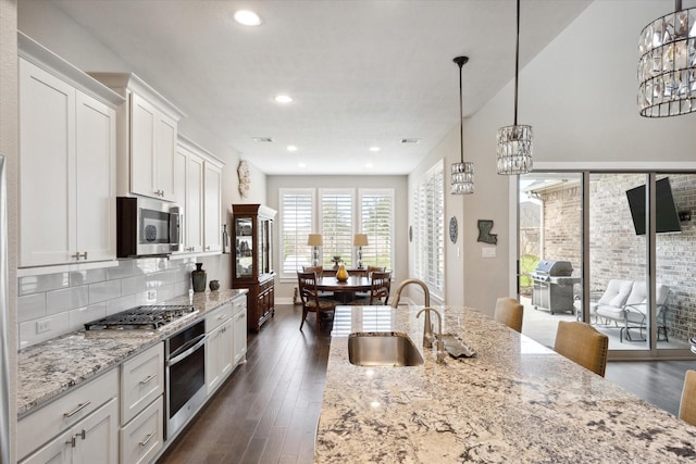 kitchen featuring pendant lighting, sink, appliances with stainless steel finishes, white cabinetry, and light stone countertops