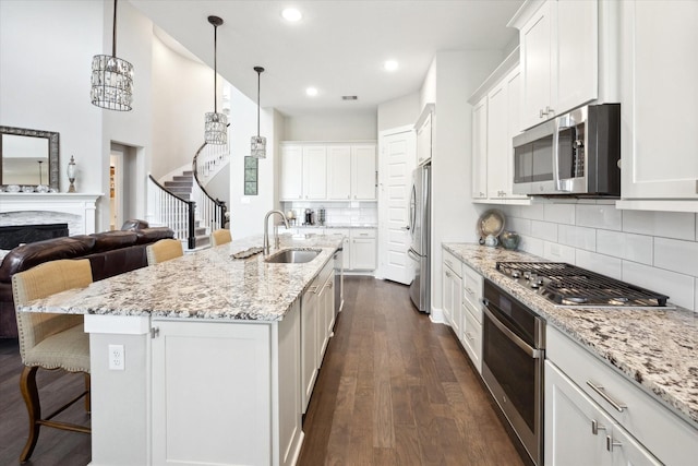 kitchen with sink, a center island with sink, white cabinets, and appliances with stainless steel finishes