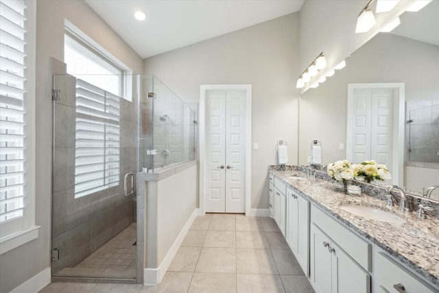 bathroom featuring tile patterned flooring, vanity, lofted ceiling, and a shower with door