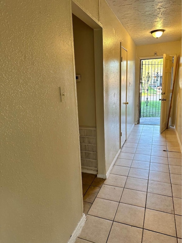 hallway featuring light tile patterned floors and a textured ceiling