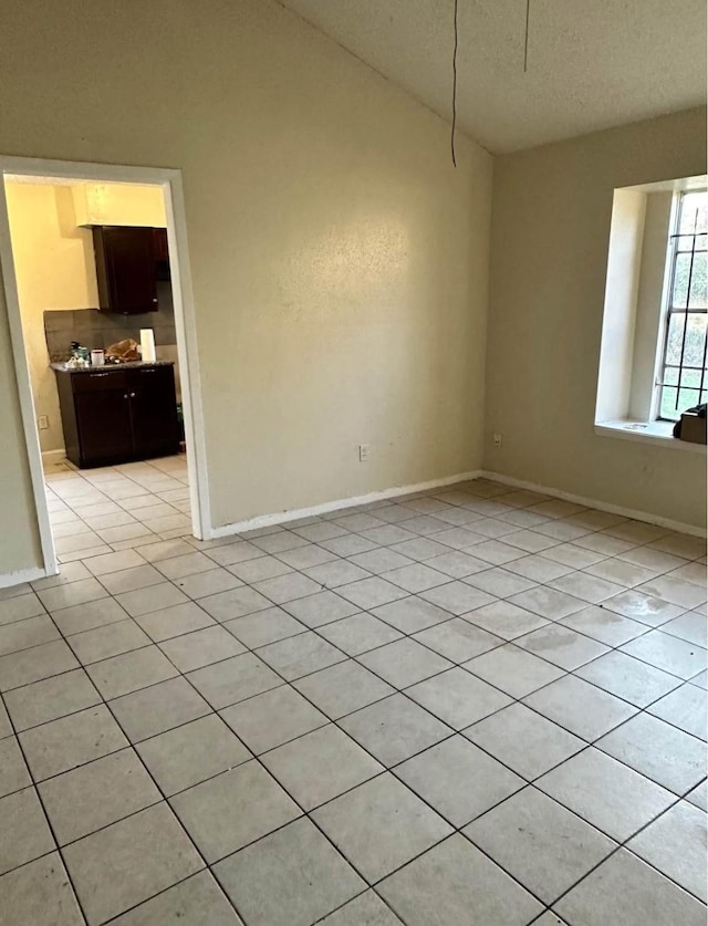 empty room featuring lofted ceiling and light tile patterned floors