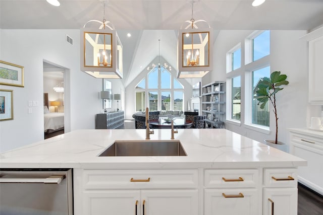 kitchen with light stone countertops, white cabinets, a notable chandelier, and decorative light fixtures