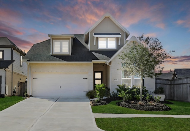 view of front of property featuring concrete driveway, a shingled roof, a lawn, and an attached garage