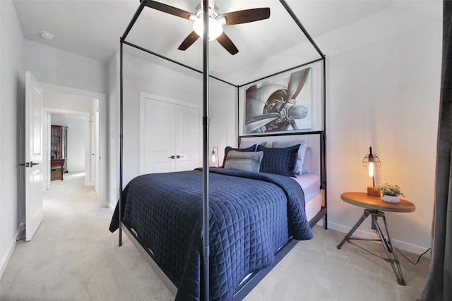 bedroom featuring a closet, light colored carpet, ceiling fan, and baseboards