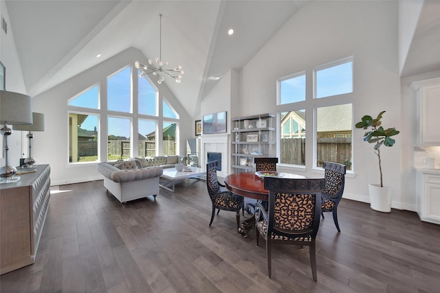 dining room with baseboards, dark wood-style flooring, an inviting chandelier, a fireplace, and high vaulted ceiling