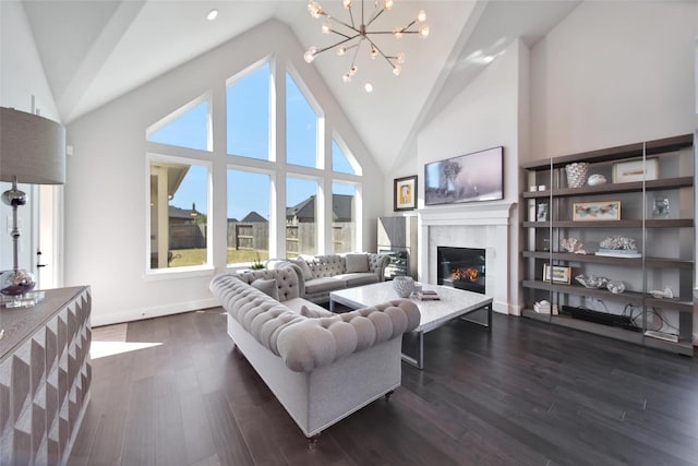 living area featuring baseboards, a tiled fireplace, dark wood-type flooring, an inviting chandelier, and high vaulted ceiling