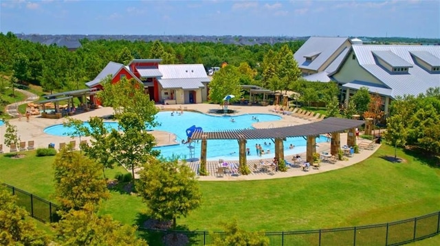 community pool with a water slide, a lawn, a patio, and fence