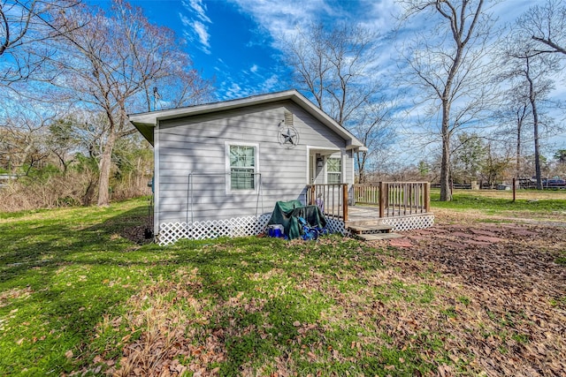 back of house with a wooden deck and a lawn