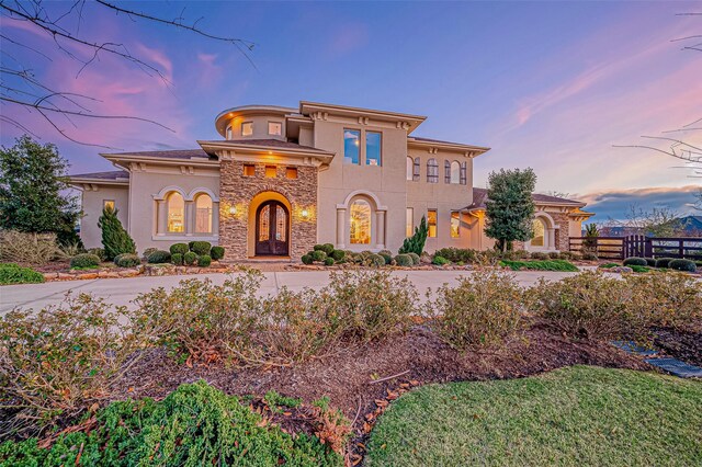 mediterranean / spanish home featuring stone siding, fence, and stucco siding