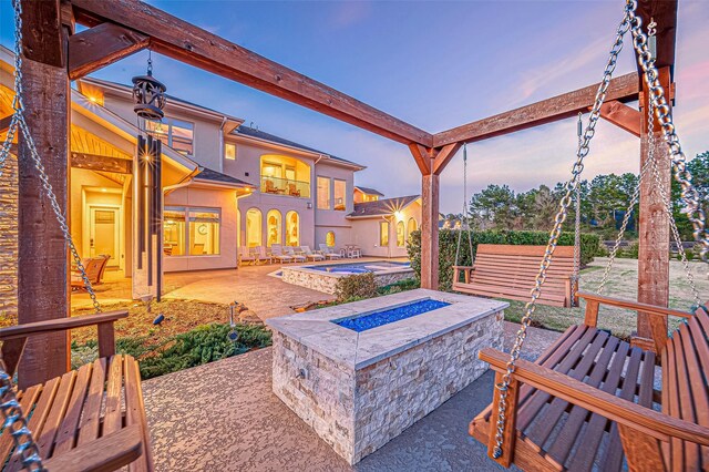 patio terrace at dusk featuring a balcony and a jacuzzi